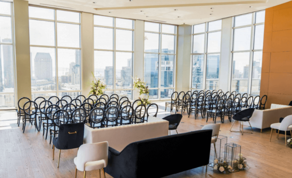 Spacious rooftop wedding reception venue with panoramic views of downtown san diego, elegantly set with modern chairs and tasteful floral arrangements